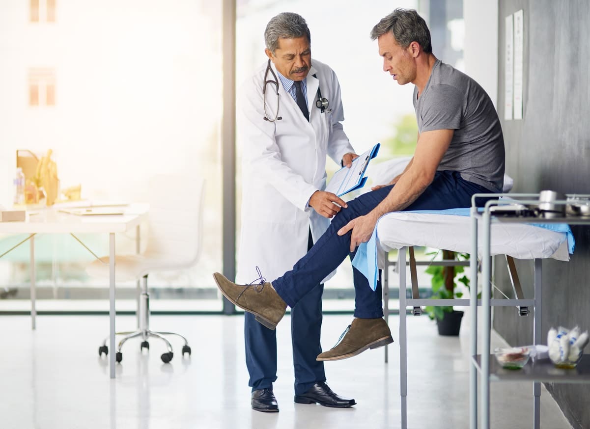 man having knee examined by doctor