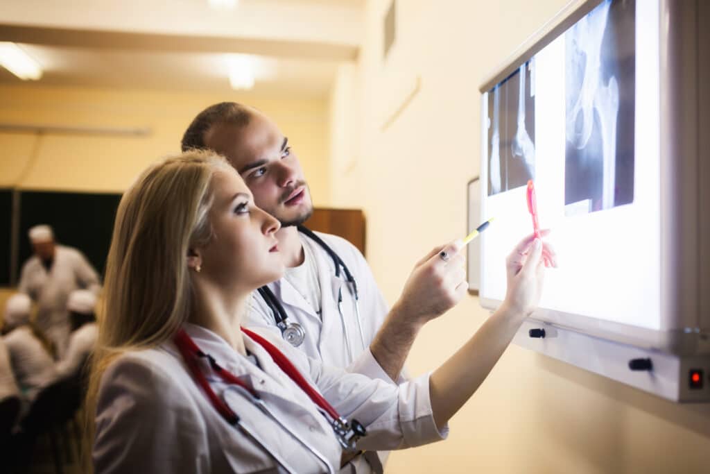 Doctor's looking at hip X-rays to diagnose necrosis and plan hip surgery
