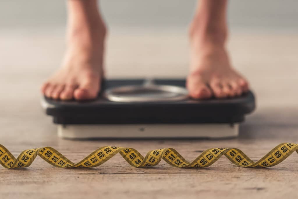 Person standing on scale and a measure tape on the floor